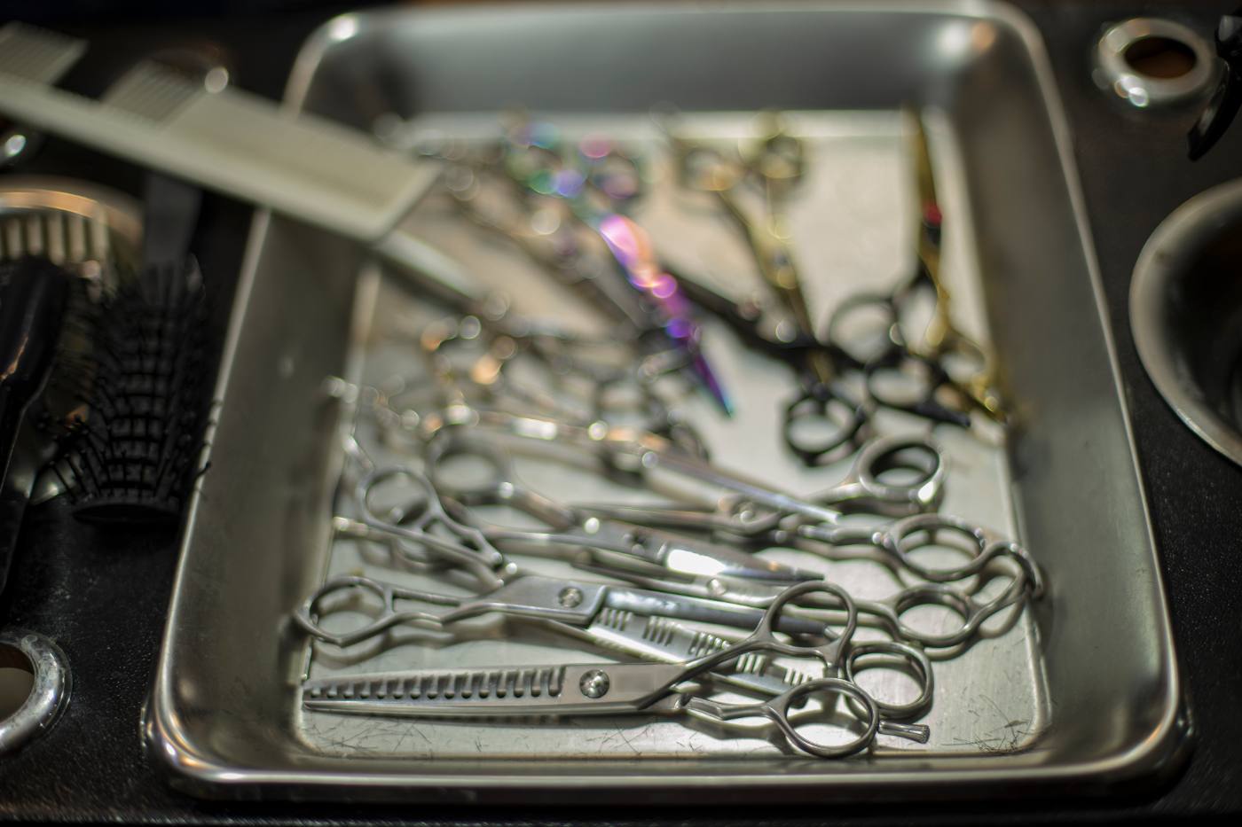 A steel tray of cutting and thinning shears at a barber's station