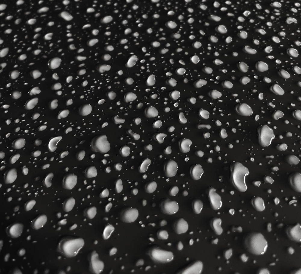Water beading into tight droplets on a coated black hood